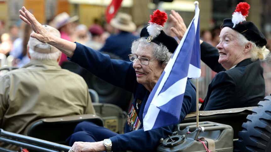 Elderly veterans wave to the crowds during an Anzac Day parade in Brisbane.