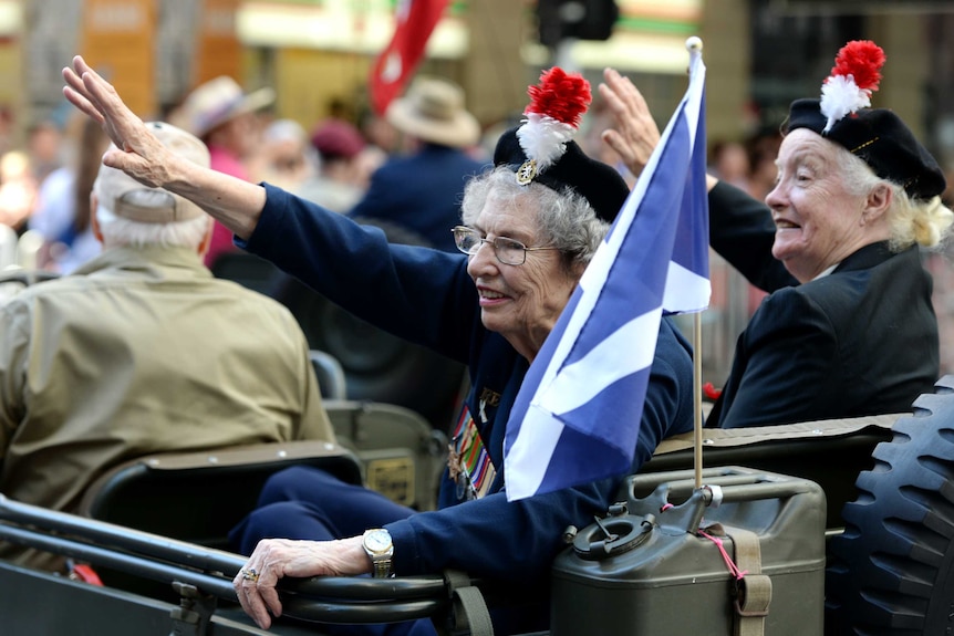 Elderly veterans wave to the crowds during an Anzac Day parade in Brisbane.