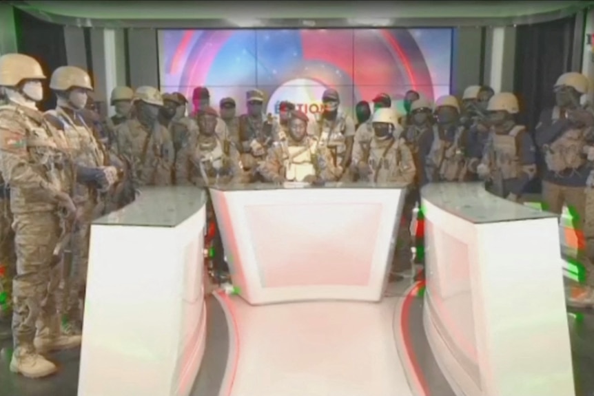 A group of soldiers appearing on television to announce the overthrow of the government. 