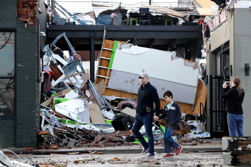 A man and boy walk passed a damaged building.