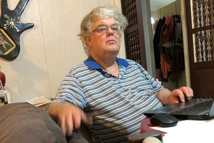 Lawrence Mack sits in front of his computer at a desk in his home.