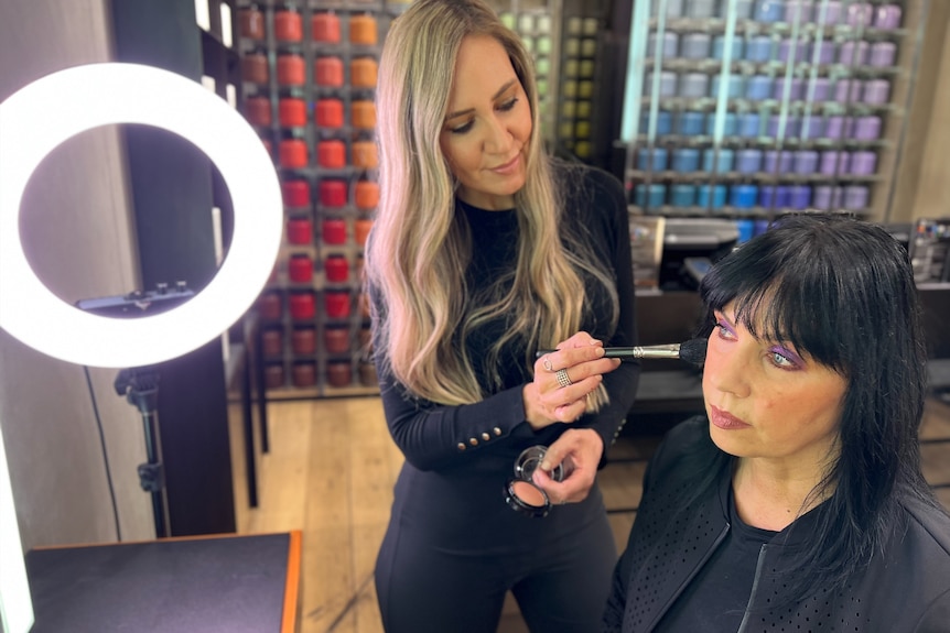 A woman applying make up to another woman