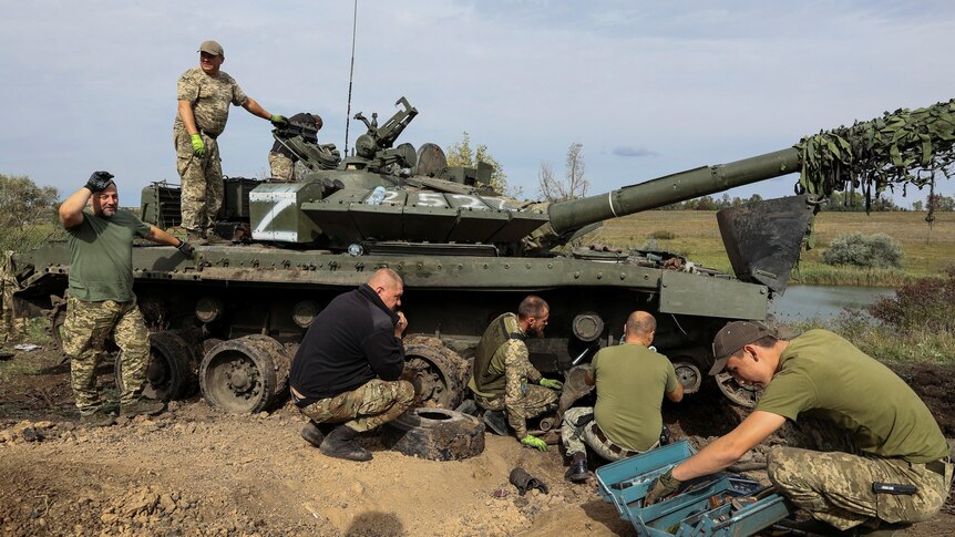 Ukrainian servicemen repair a captured Russian tank.