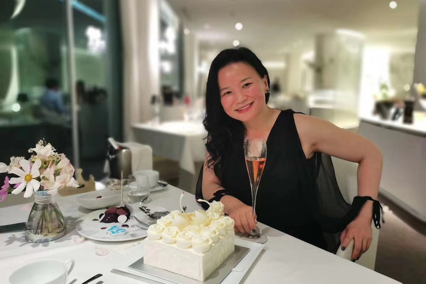 Cheng Lei sitting at a table with a cake.
