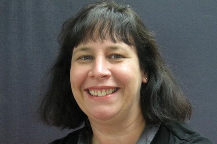 A close-up of a middle-aged woman with shoulder-length black hair.