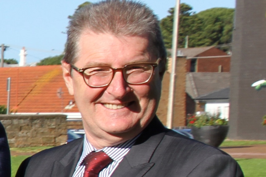 A man in a suit smiles at the camera.