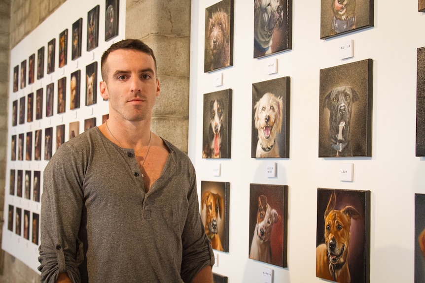 Artist Stephen Gallagher stands in front of his 100 dog paintings.