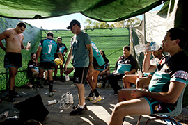 A group of rugby players getting changed under a green tarpaulin