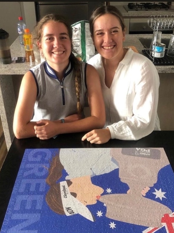 Golfer Hannah Green sits over a completed puzzle of herself and smiles.