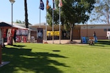The lawn of the Alice Springs Town Council building. A yellow banner hung across flag poles says polling place.