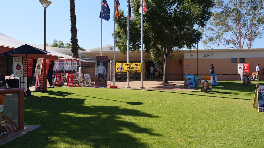 The lawn of the Alice Springs Town Council building. A yellow banner hung across flag poles says polling place.