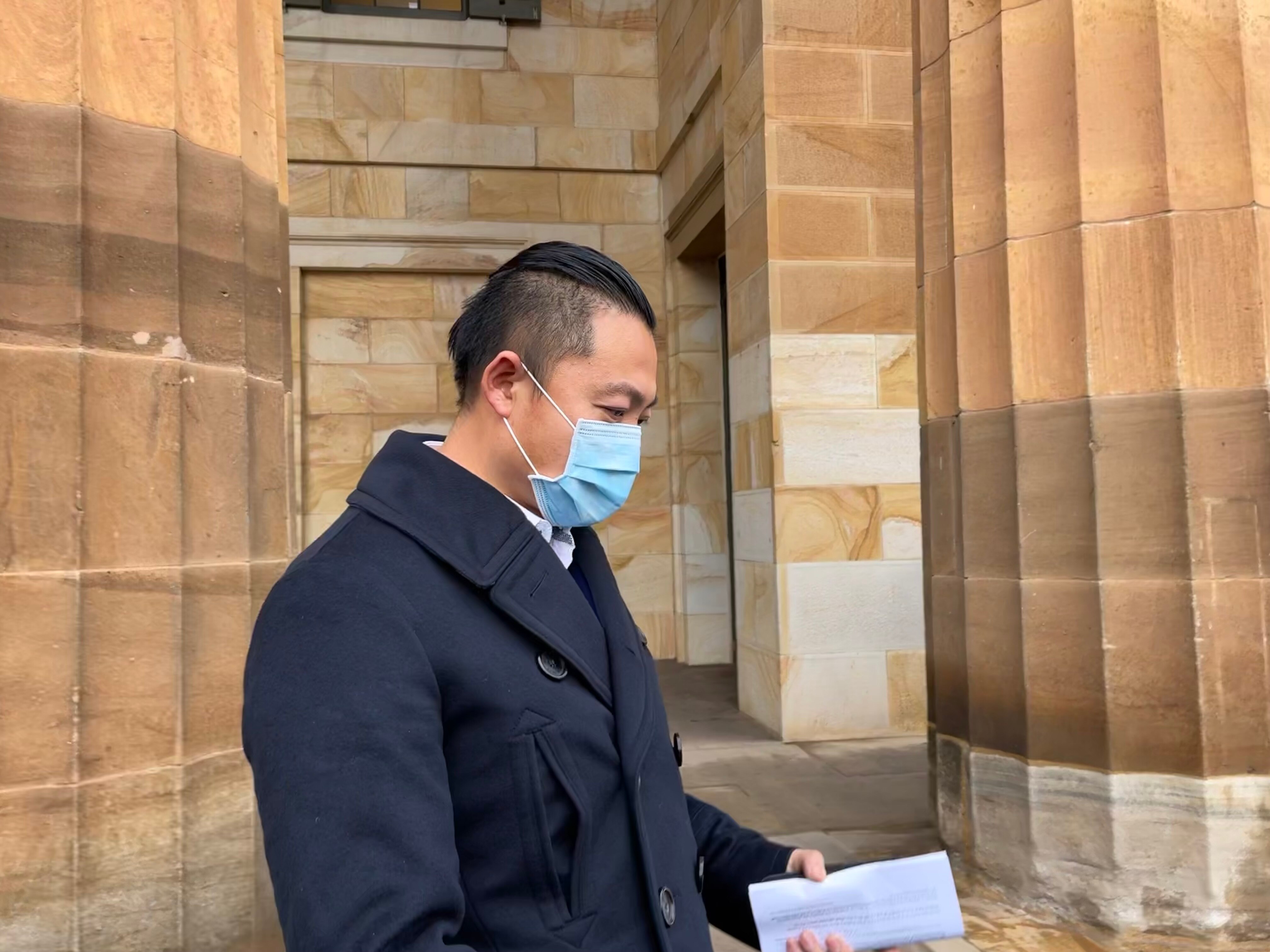 A man in a face mask standing outside of court