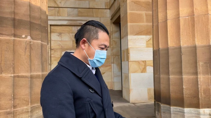 A man in a face mask standing outside of court