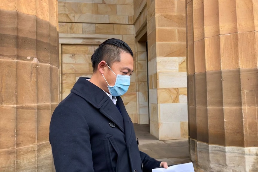 A man in a face mask standing outside of court