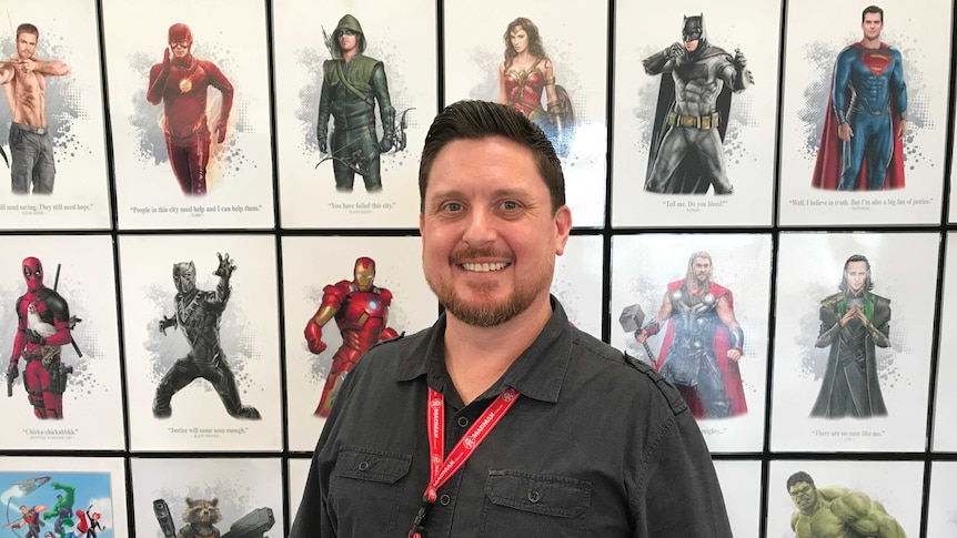 Australian comic artist Stewart McKenny in front of many realistic pictures he's made.