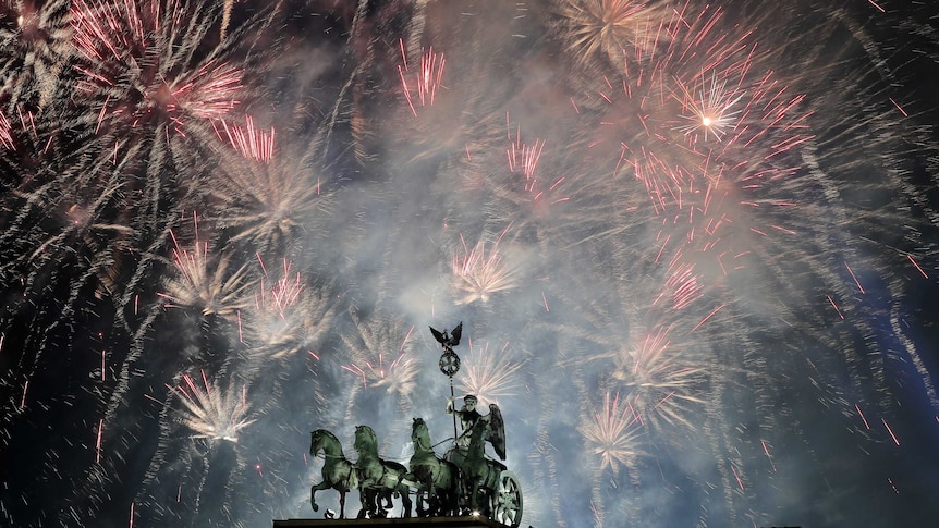 Berlin's Brandenburg gate is back-lit by bright fireworks filling the sky.