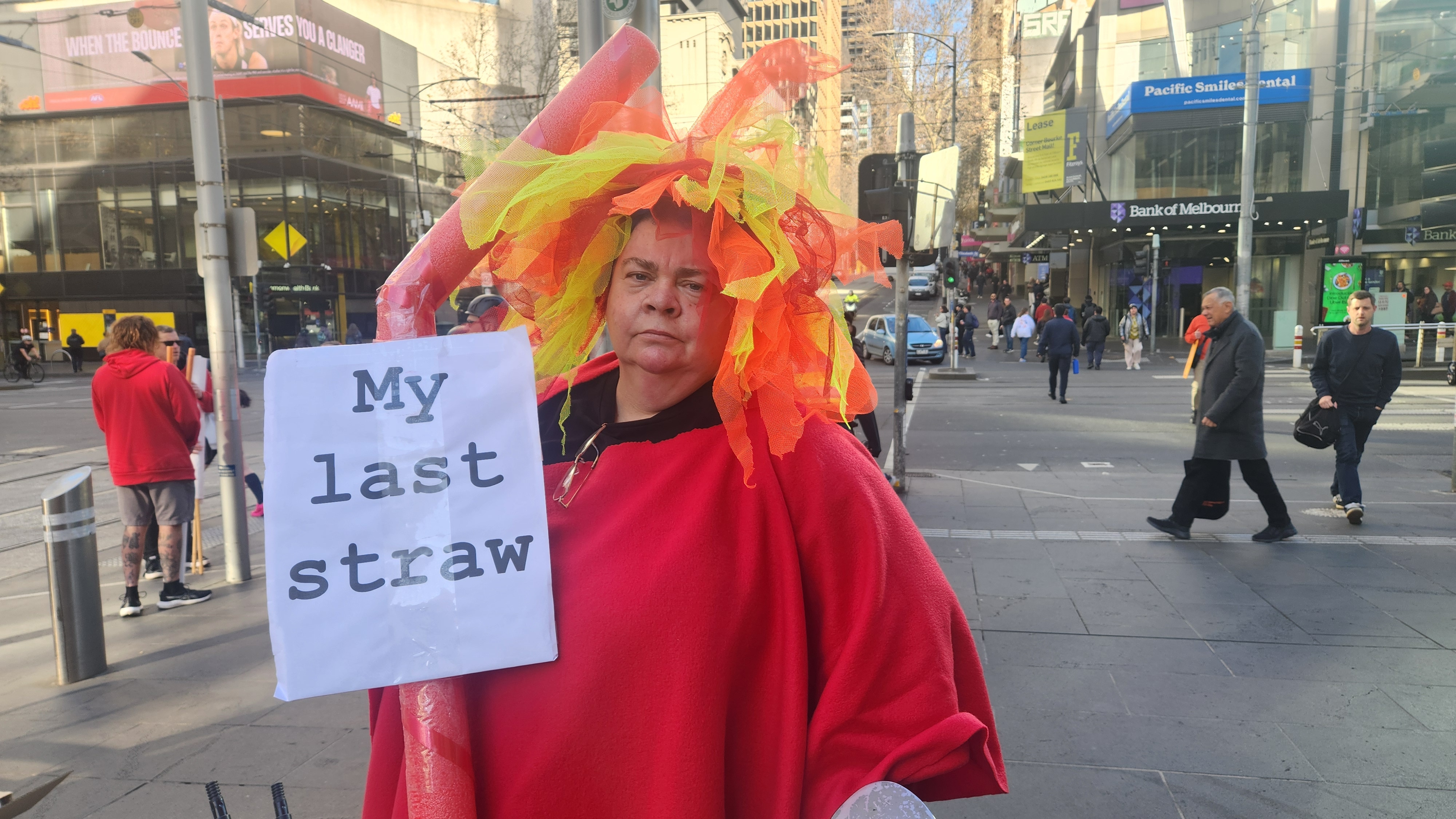 A woman holds a huge straw and a sign that says: 