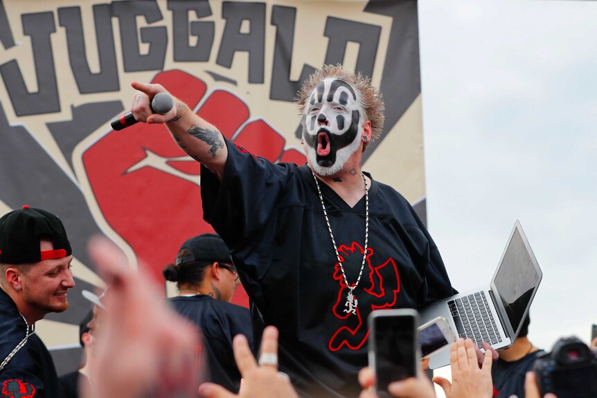 Violent J sports a black and white clown face and yells down into the crowd