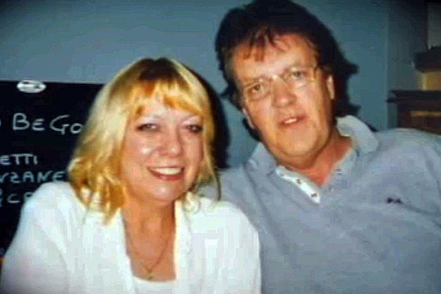 A grainy photo of a smiling blonde woman and a man with glasses.