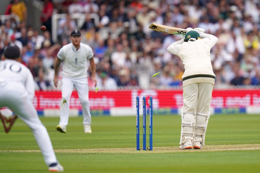 Australia batter Usman Khawaja is seen from behind as a cricket ball hits his stumps during an Ashes Test.