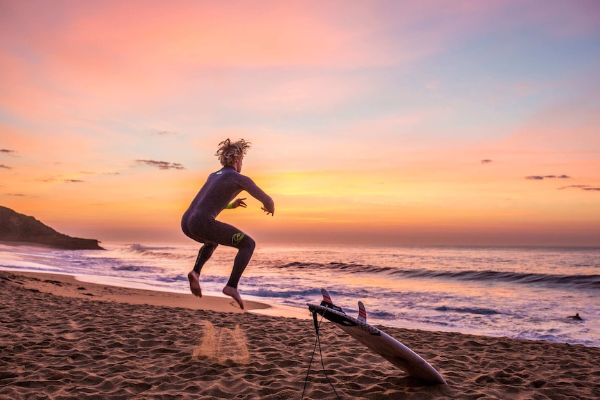 Surfer Cody Robinson jumps up on Bells Beach before hitting the waves.