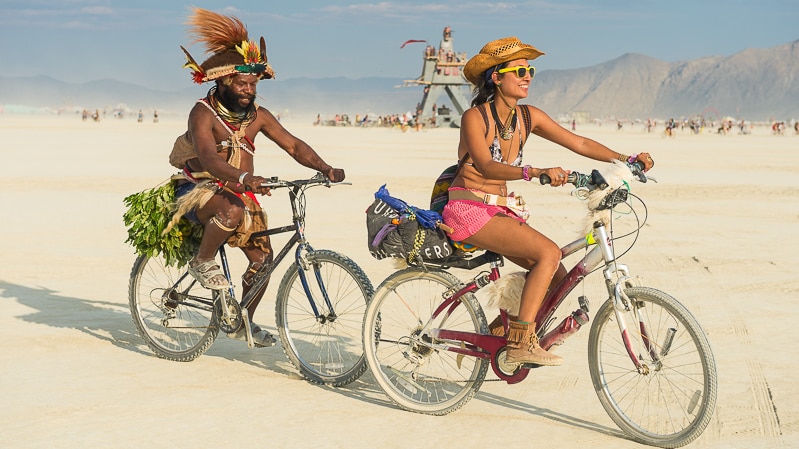 PNG Highlands chief Mundiya Kepanga rides a bike with a woman at Burning Man festival, Black Rock City, Nevada