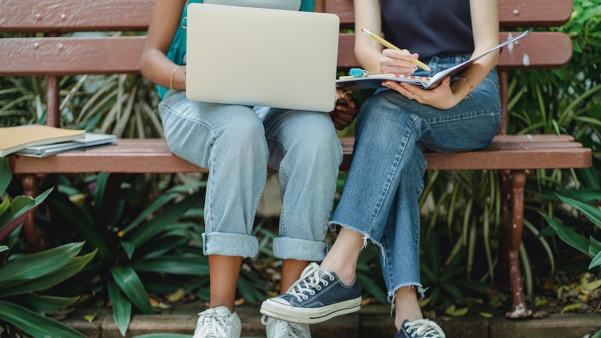 People sit with a laptop and crossed legs.