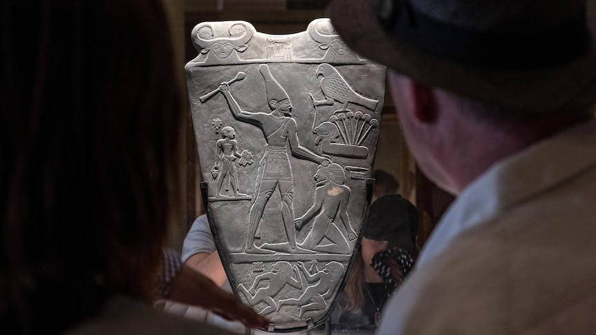 Two people look at an engraved stone slab. 