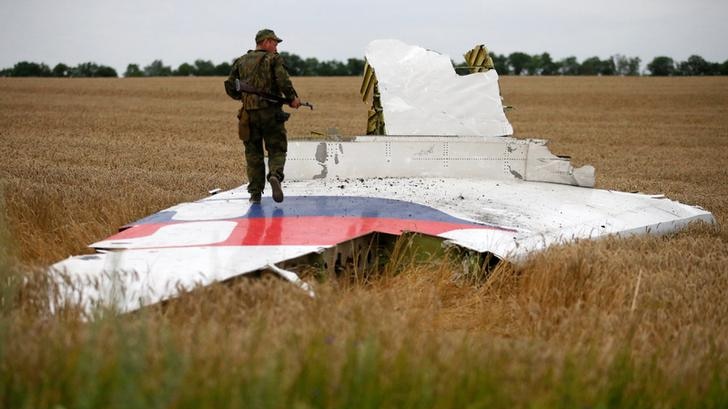 An armed man walks on the wing of downed MH17 plane