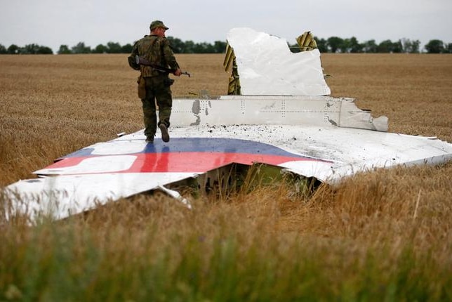 An armed man walks on the wing of downed MH17 plane