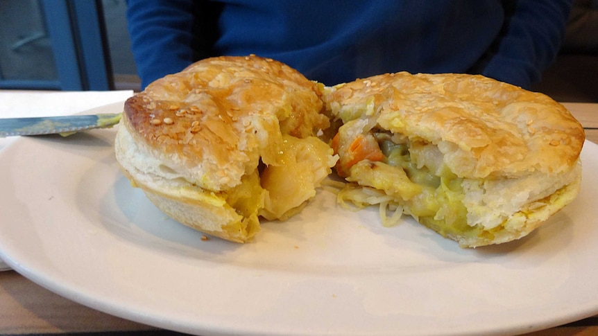 A curried scallop pie cut in half on a white plate