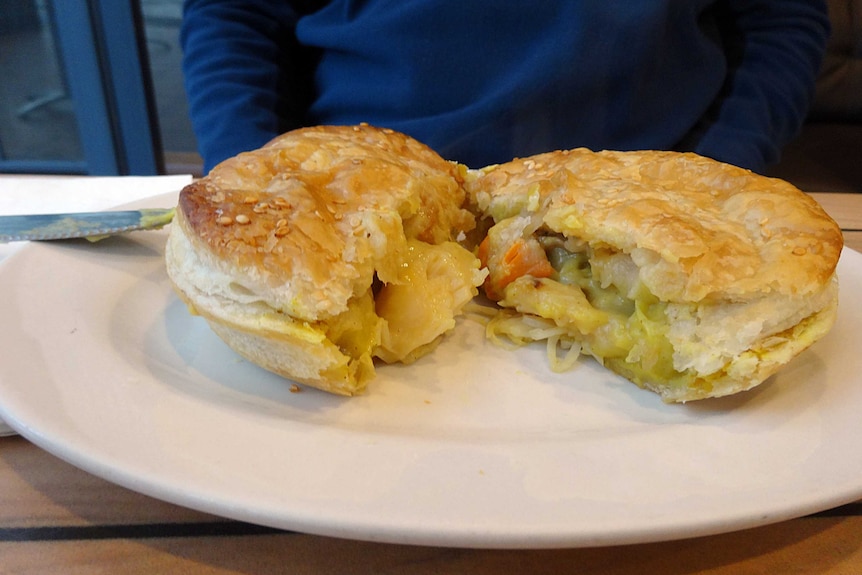 A curried scallop pie cut in half on a white plate