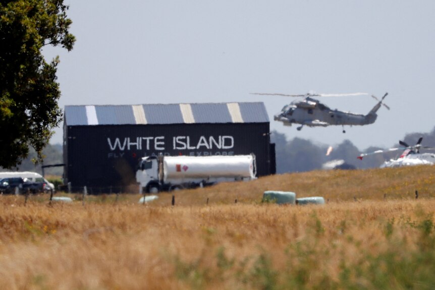 A helicopter can be seen taking off near a shed that reads 'White Island'