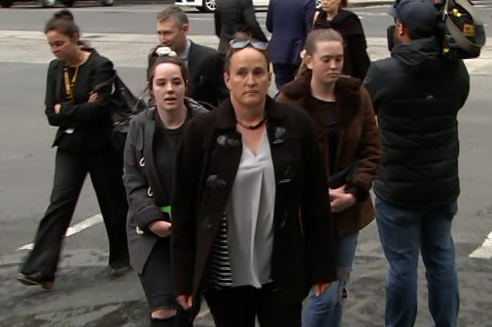 A woman walking in the street with other women next to her.