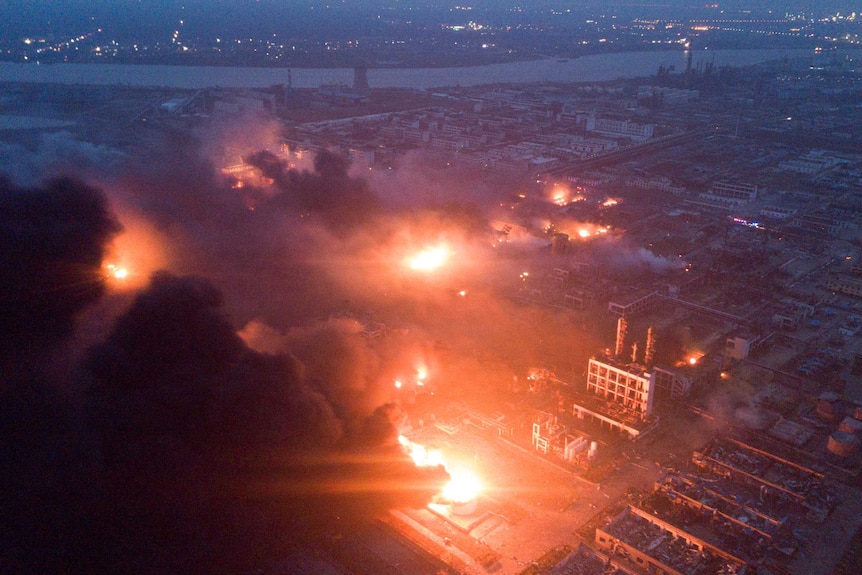 Overhead shot of fire blazing and smoke billowing in front of a night sky at the pesticide plant.