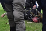 A man is held down by police officers as part of an arrest.