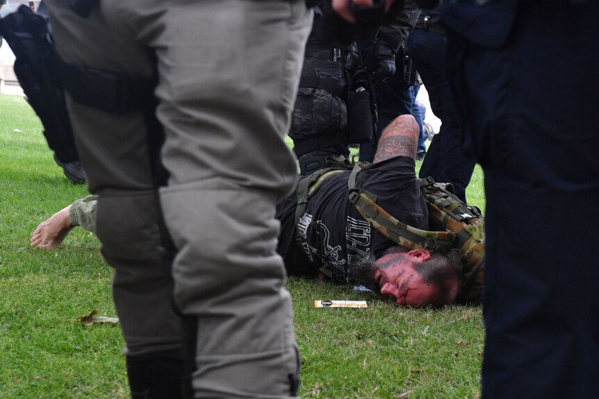 A man is held down by police officers as part of an arrest.
