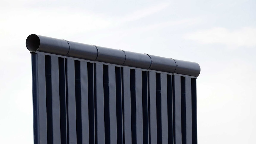 A metal wall features six light blue squares with white trim on the bottom third, topped by dark blue beams and metal plates.