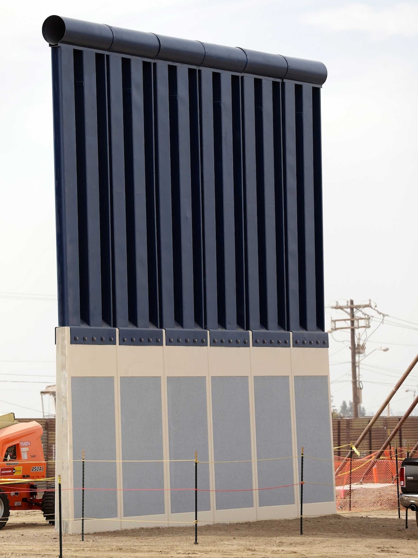 A metal wall features six light blue squares with white trim on the bottom third, topped by dark blue beams and metal plates.