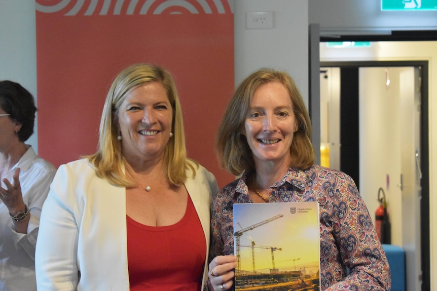 Dr Donna Bridges holds a report while standing nest to Bronwyn Taylor.