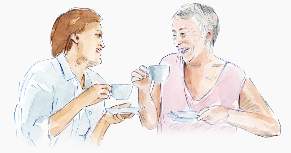 Two women drinking tea and laughing together.