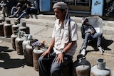 A man sits on a line of gas bottles in a street in Yemen.