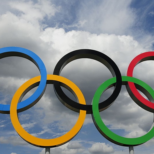 The Olympic rings against a cloudy sky.