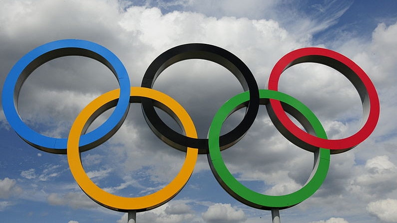 The Olympic rings against a cloudy sky.