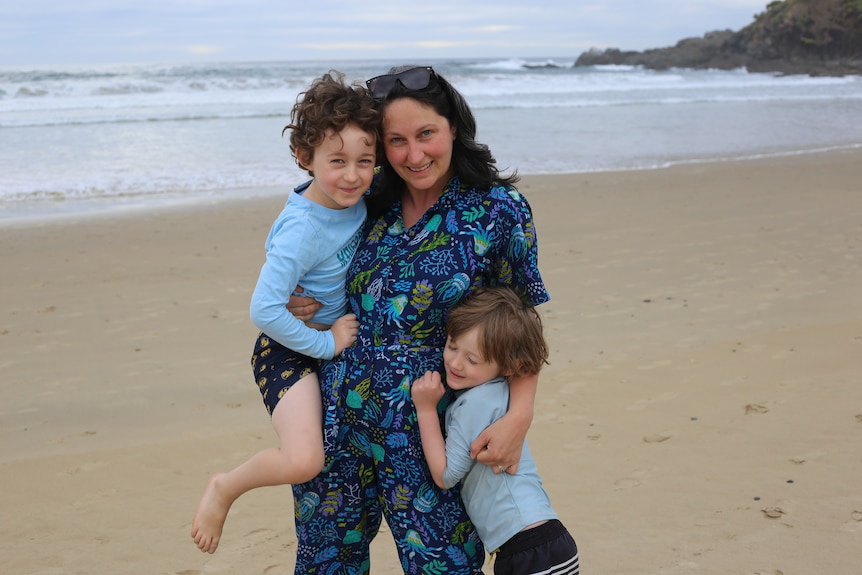 Mary Bolling hugging her two sons on the beach