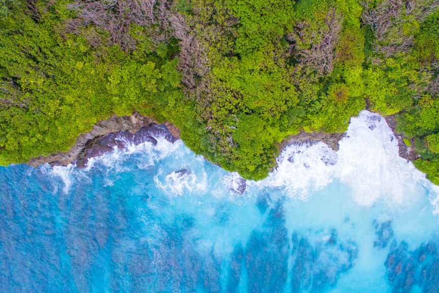 An aerial shot over Christmas Island showing aqua waters and green scrubland