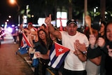 Crowd waves Cuban flags on the street.
