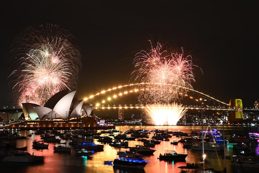 A spectacular view of Sydney Harbour shows the Opera House and Harbour Bridge illuminated by golden fireworks.