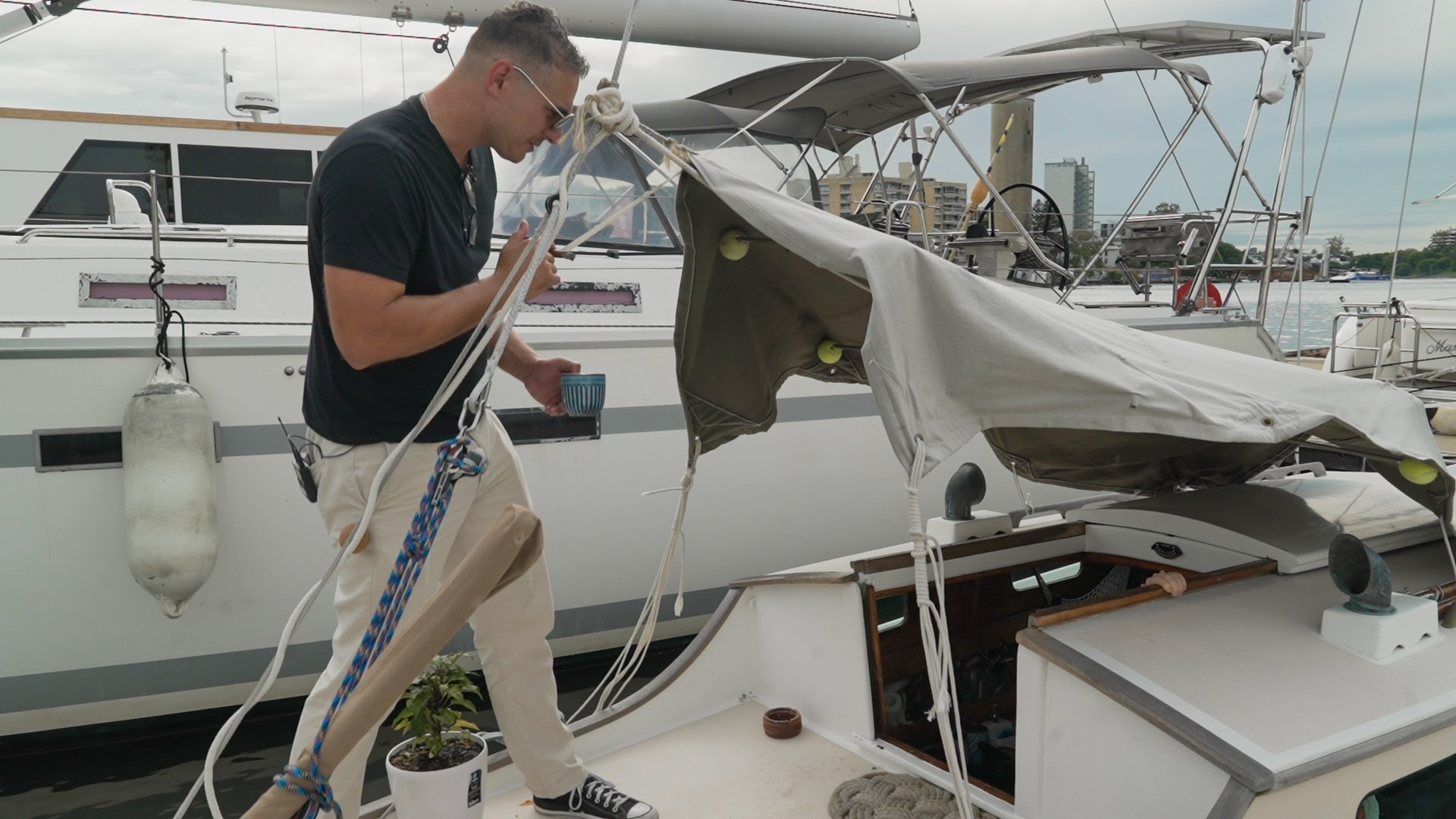 Un hombre con una camiseta oscura se encuentra en la cubierta de un yate.