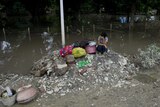 A resident sits on high ground near a flooded area in Kalay